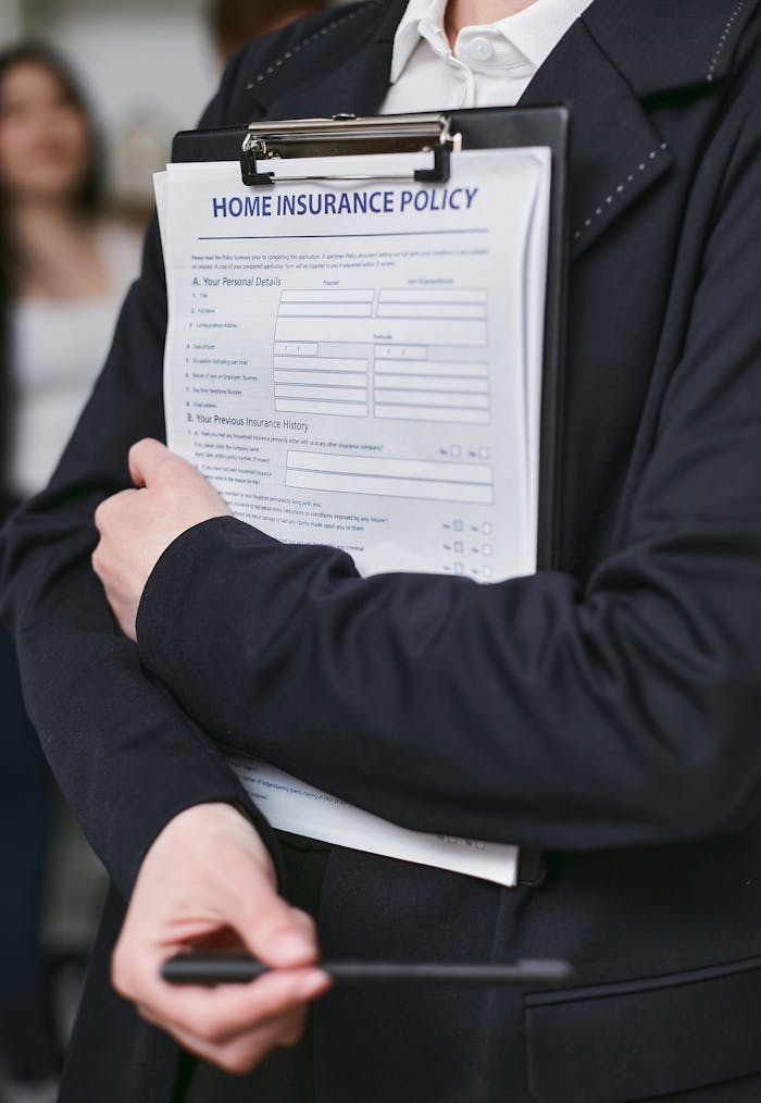 Close-up of a person holding a home insurance policy on a clipboard indoors.