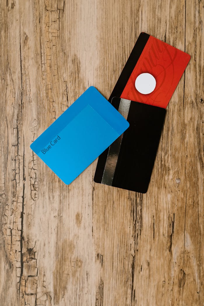 Flat lay of a red wallet and credit cards on a rustic wooden surface, offering room for text.