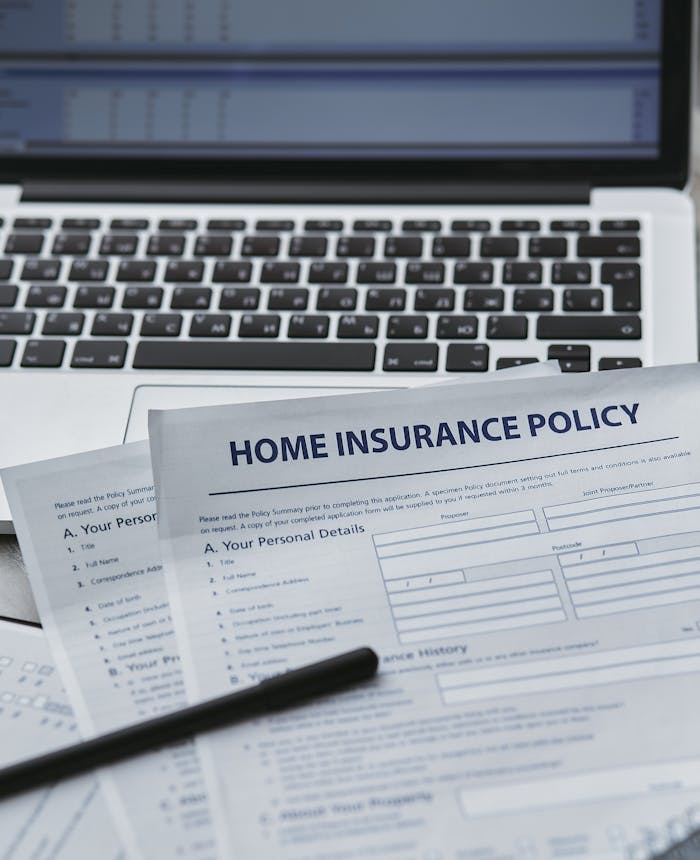 Close-up of home insurance documents with a laptop, symbolizing modern paperwork processes.